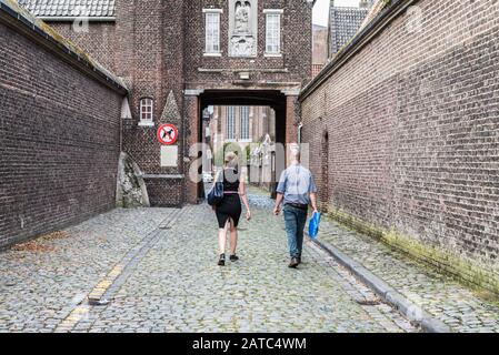 Gand, Flandre / Belgique - 09 02 2019: Jeune homme et femme sortant de la porte du béguinage de Saint Elisabeth et Saint Amandsberg Banque D'Images