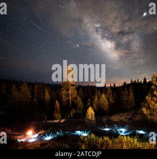 Milky Way et Shooting Star au-dessus des lumières Festives et un feu de camp, Kings Canyon, Sequoia National Park, Californie, États-Unis Banque D'Images