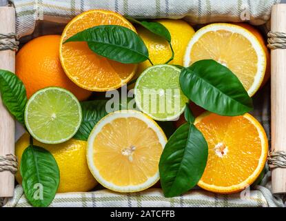 Tranches d'agrumes dans un panier. Pose plate. Tranches mûres juteuses d'orange, de citron et de citron vert. Mélange de fruits, vue de dessus. Contexte alimentaire. Banque D'Images