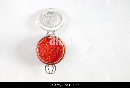 Sauce au piment chaud, pâte harissa. Adjika. Cuisine traditionnelle tunisienne, géorgienne et arabe. Harissa de rose maison dans un pot en verre. Banque D'Images