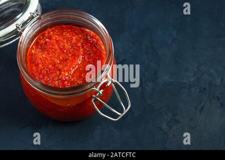 Sauce au piment chaud, pâte harissa. Adjika. Cuisine traditionnelle tunisienne, géorgienne et arabe. Espace de copie. Fond bleu. Banque D'Images