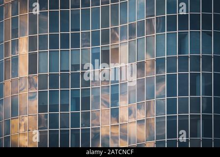 Les lumières de l'après-midi se reflètent sur la façade en verre incurvée d'un immeuble de bureaux Banque D'Images