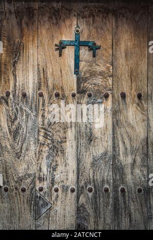 Porte en bois antique décorée d'une croix en fonte et de clous en fer Banque D'Images