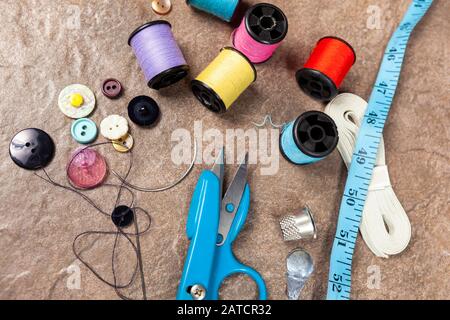 Aiguilles et bobines de coton coloré sur une table de travail avec un ruban de désordre et de thimble Banque D'Images