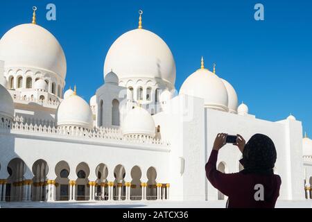 Femme de tourisme en photo sur téléphone mobile de la Grande Mosquée Sheikh Zayed à Abu Dhabi, aux Emirats Arabes Unis Banque D'Images