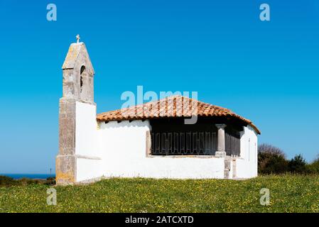 Ancienne chapelle blanche près de la rive dans le champ plein de fleurs jaunes par temps clair Banque D'Images