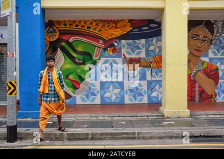 Un invité indien habillé pour une visite du temple passant par une peinture murale sur le thème sud de l'Inde; dans Upper Dickson Road, Little India, Singapour Banque D'Images