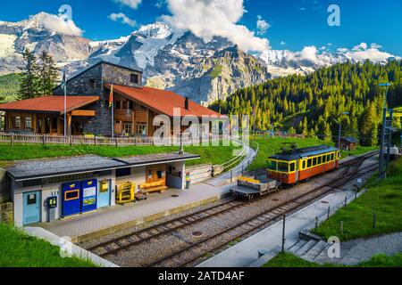 Belle montagne de la gare de Winteregg avec un restaurant en bois confortable et de hautes montagnes enneigées en arrière-plan. Train touristique rétro dans la stat de train Banque D'Images