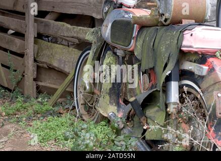 Une vieille moto Honda de 125 cc de 125 cc, recouverte de mousse, sur le côté d'une grange, dans le sud-ouest de l'Alabama. Banque D'Images
