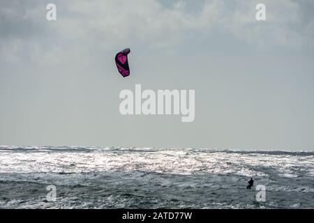 Un kitéboarder ou un paraborder navigue sur les vagues de cornish. ROYAUME-UNI Banque D'Images