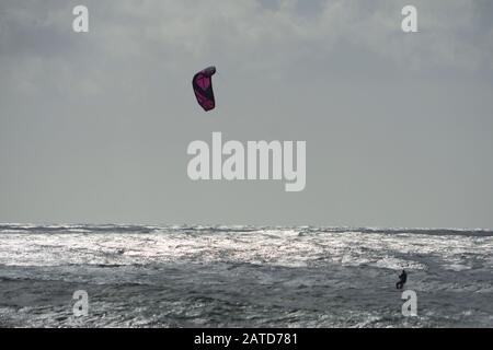 Un kitéboarder ou un paraborder navigue sur les vagues de cornish. ROYAUME-UNI Banque D'Images