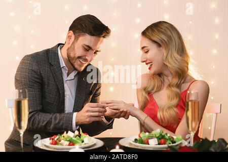 L'Homme Met L'Anneau D'Engagement Sur La Main De La Petite Amie À Date Dans Le Restaurant Banque D'Images