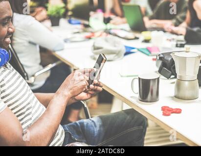 Heureux étudiant africain utilisant le téléphone mobile à l'université pendant la pause du matin - jeunes travaillant ensemble au projet de blog - Focus sur l'homme à droite Banque D'Images