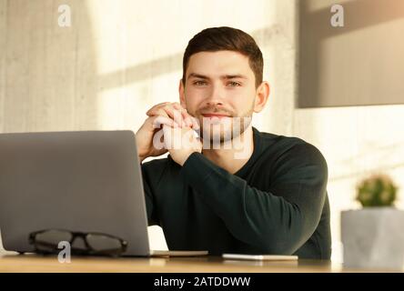 Jeune Homme À Un Ordinateur Portable Assis Au Bureau Dans Un Bureau Moderne Banque D'Images