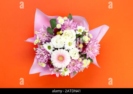 un bouquet de fleurs différentes dans un emballage en papier. sur fond orange. endroit pour le texte Banque D'Images