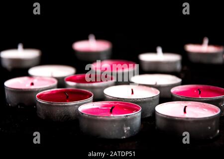 Un ensemble de bougies de paraffine chauffe-plat rose sur fond noir. Banque D'Images