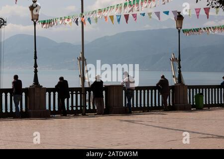 Les hommes se tiennent contre les anciennes balustrades françaises qui surplombent le port de Bejaia, la ville portuaire sur la côte nord de la Méditerranée en Algérie. Banque D'Images