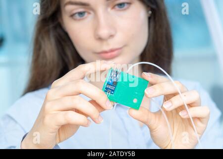 Femme Jeune scientifique en laboratoire microbiologique avec lab-on-chip LOC microfluidic device Banque D'Images