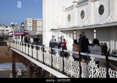 Les gens marchent le long de la jetée sur un Sunny Day avec des mers rugueuses à Brighton, East Sussex, Royaume-Uni Banque D'Images