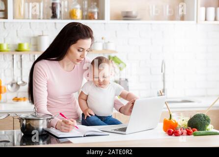 Femme occupée qui tente de noter le projet avec un enfant de la fidgeté Banque D'Images