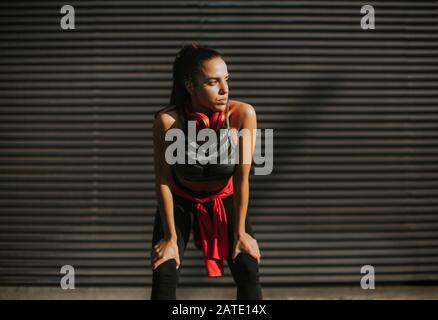 Une jeune femme assez jeune prend une pause après avoir courir dans la zone urbaine Banque D'Images
