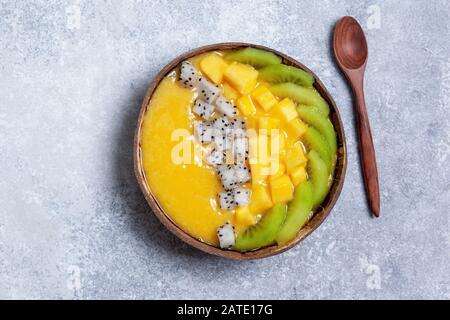 bol à smoothie à la mangue avec kiwi, fruits du dragon et fruits de la passion sur fond gris en béton. vue du dessus Banque D'Images