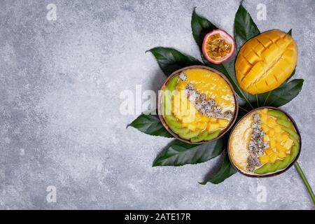 bol à smoothie à la mangue avec kiwi, fruits du dragon et fruits de la passion sur fond gris en béton. vue du dessus Banque D'Images