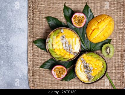 bol à smoothie à la mangue avec kiwi, fruits du dragon et fruits de la passion sur fond gris en béton. vue du dessus Banque D'Images