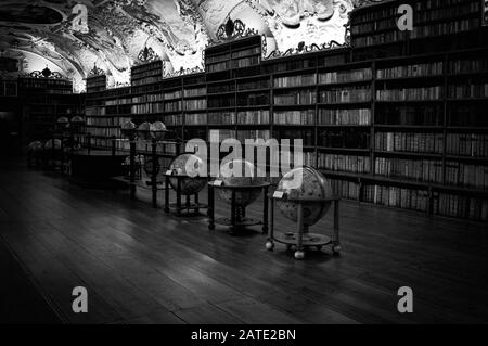 Prague, République tchèque - 30 décembre 2019: Ancienne bibliothèque avec globes et beaucoup de livres à l'intérieur des étagères décorées (salle théologique, bibliothèque Strahov) Banque D'Images