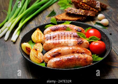 Saucisses frites dans la poêle sur table en bois, gros plan Banque D'Images