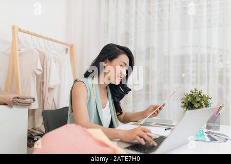 Une femme d'affaires / Asian Fashion designer travaillant à son bureau / Atelier Banque D'Images