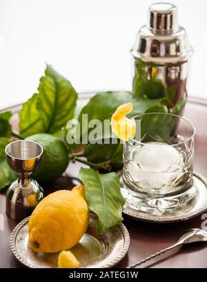 Un verre de whisky en cristal avec un grand morceau de glace sphérique et une garniture d'agrumes. Banque D'Images