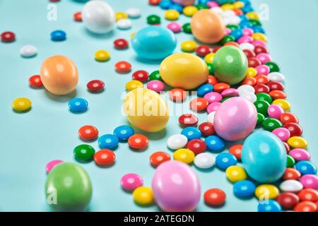 De la vue ci-dessus de grandes et petites boules de chocolat aux arachides dans la coquille de sucre croustillante colorée isolée sur fond bleu. Foyer sélectif de grande quantité de délicieux bonbons. Concept de la nourriture. Banque D'Images