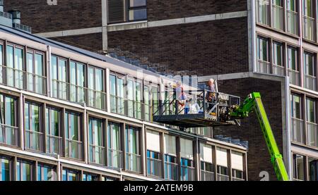 Travailleurs sur une plate-forme d'ascenseur, réparations sur un complexe d'appartements dans la ville d'Amsterdam, aux Pays-Bas Banque D'Images