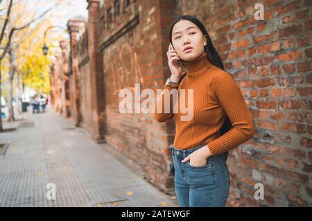 Portrait of young Asian woman parler au téléphone à l'extérieur dans la rue. Concept urbain et de la communication. Banque D'Images