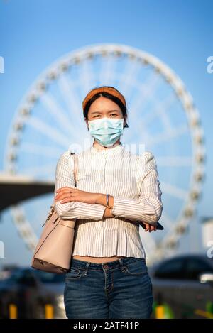 Fille asiatique portant un masque pour empêcher le virus à la gare routière Banque D'Images