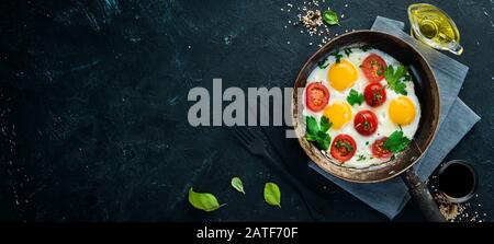 Œufs avec tomates et légumes verts dans une poêle à frire. Banque D'Images