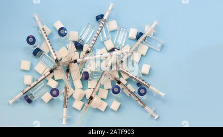 Dépendance au sucre, résistance à l'insuline, régime alimentaire malsain, cubes de sucre, bouteilles d'insuline et seringue pour la vaccination sur fond bleu, protecti du diabète Banque D'Images