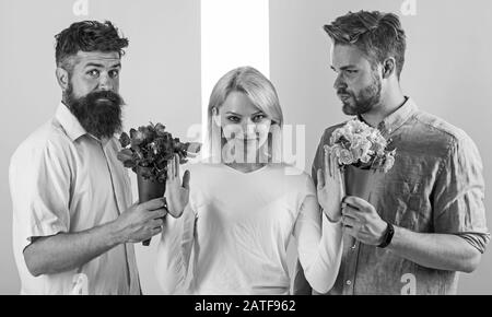 Les filles populaires reçoivent beaucoup d'attention des hommes. Hommes concurrents avec bouquets fleurs essayer de conquérir fille. Fille souriante rejeter des cadeaux. Concept du féminisme. Une femme souriante rejette les deux partenaires masculins. Hors des relations. Banque D'Images