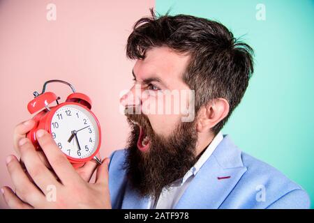 La gestion du temps. Combien de temps jusqu'à ce délai. Le temps de travail. L'homme d'affaires agressif barbu tenir réveil. Le concept de stress. Horaire de travail stressantes hipster. Businessman a faute de temps. Banque D'Images