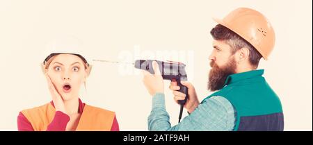 Homme avec forets tête de femme, fond blanc. Femme avec un visage choqué dans le casque, le casque. Builder, repairman fait trou dans la tête femelle. Concept de réparation ennuyeux. Mari agacé femme. Banque D'Images