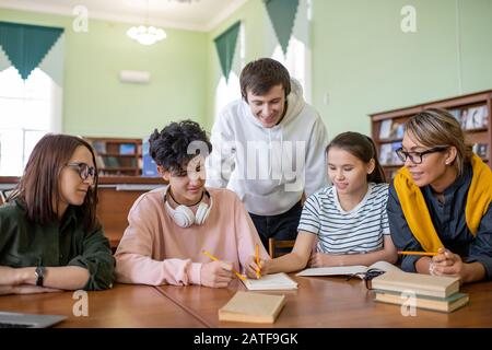 Grand groupe d'apprenants adolescents se préparant à un séminaire à la bibliothèque de l'université Banque D'Images