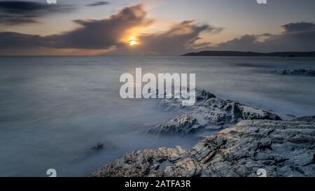 Milky mer au coucher du soleil sur les rochers à Bovisand dans Devon Banque D'Images