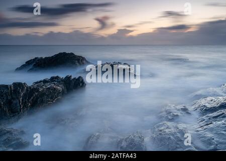 Milky mer au coucher du soleil sur les rochers à Bovisand dans Devon Banque D'Images