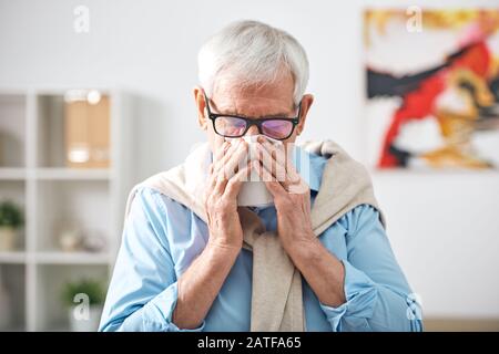 Un homme malade à la retraite avec mouchoir par son nez restant à la maison Banque D'Images