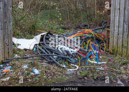 Plastique, métal, câbles, pneus et ordures déversés illégalement à bout de mouche à la campagne. Compstall, Stockport, Cheshire, Royaume-Uni. Banque D'Images