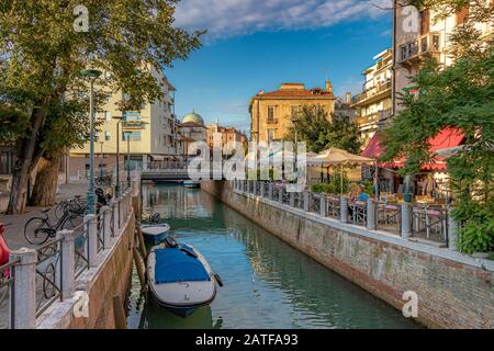 Les gens dans un restaurant le long du canal sur Via Vettor Pisani, Lido, Venise, Italie Banque D'Images