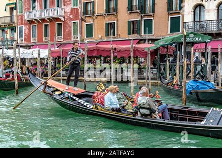 Les touristes qui aiment faire un tour en gondole tandis que le gondolier emmène sa télécabine à travers le Grand Canal animé de Venise, Venise, Italie Banque D'Images