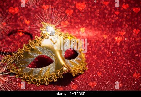 Masque doré vénitien sur fond pailleté rouge Banque D'Images