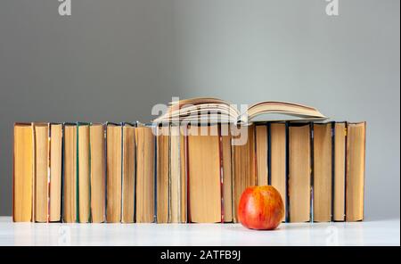 Livre ouvert, journal, pages bronzées sur pile de livres sur table blanche avec pomme rouge. Empilage de livres. Retour au concept scolaire. Espace De Copie. Éducation Banque D'Images